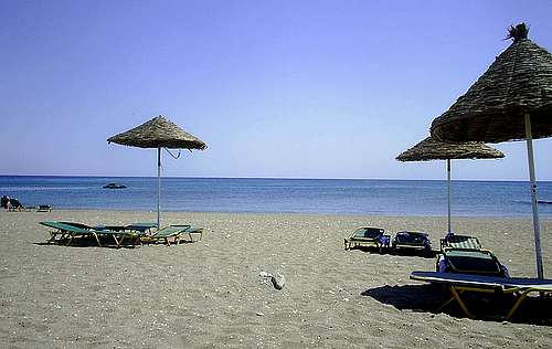 Řecká pláž se slunečníky a lehátky